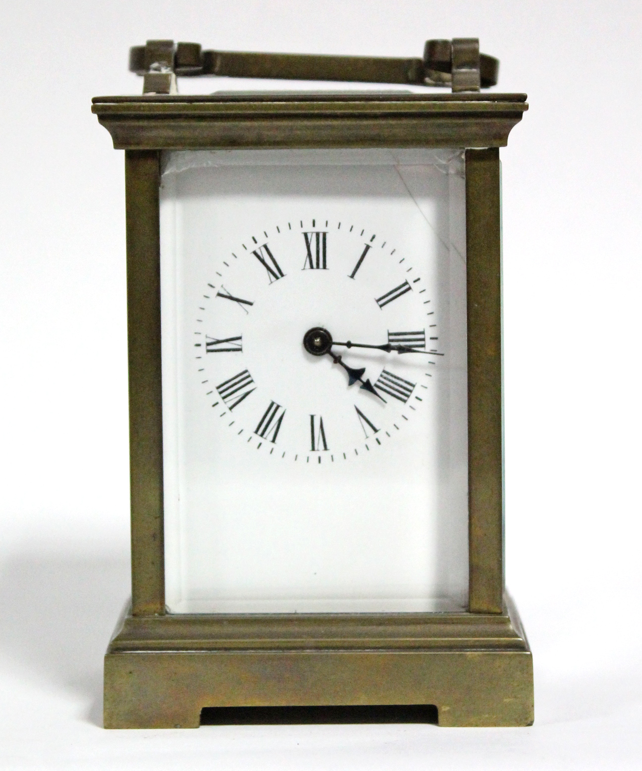 A brass carriage timepiece with black roman numerals to the white enamel dial; 4½” high.