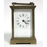 A brass carriage timepiece with black roman numerals to the white enamel dial; 4½” high.