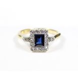 An early 20th century sapphire ring, the emerald-cut stone within a rectangular border set small
