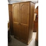 A pine wardrobe enclosed by pair of fielded panel doors, & on shaped plinth base, 35½” wide x 70½”