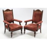 A pair of Edwardian carved walnut frame armchairs with padded back, arms, & sprung seats upholstered