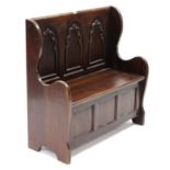 A teak box-seat settle with carved panel back, hinged lift-seat & on shaped end supports, 36¼”