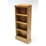 A pine small standing four-tier open bookcase on shaped plinth base, 25¼” wide x 55” high.
