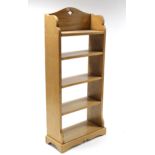 A fruitwood tall standing five-tier open bookcase with shaped end supports, & on shaped plinth base,