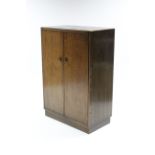 A mid-20th century oak millinery cupboard with fitted interior enclosed by pair of panel doors, & on
