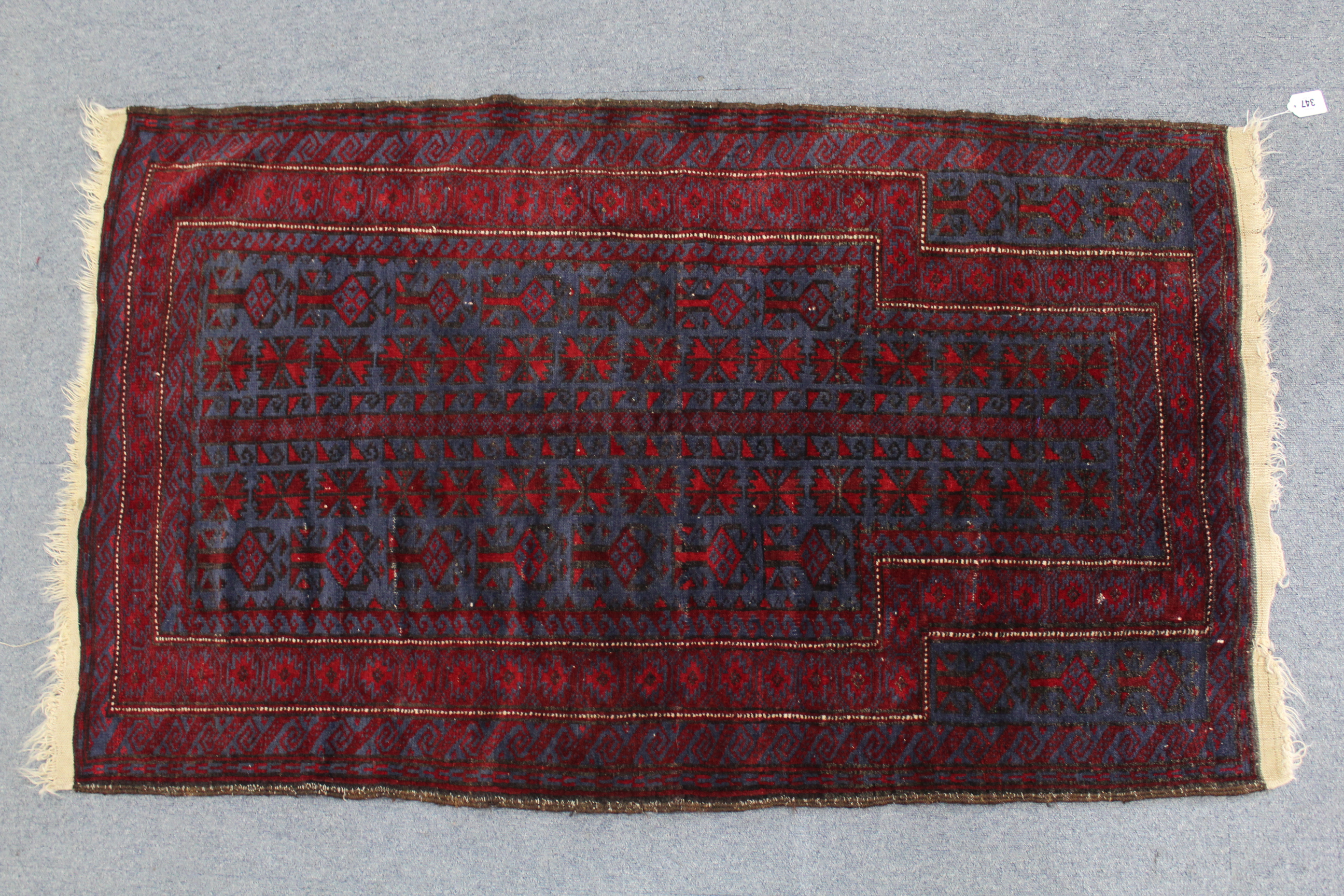 A Persian pattern rug of crimson & blue ground, with repeating geometric design to centre within a