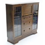 A mid-20th century oak side cabinet, with fitted interior to centre enclosed by fall-front above