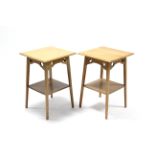 A pair of Edwardian light oak square two-tier occasional tables, each on four square tapered legs,