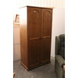 A pine wardrobe enclosed by pair of fielded panel doors, & on shaped plinth base, 35½” wide x 70½”