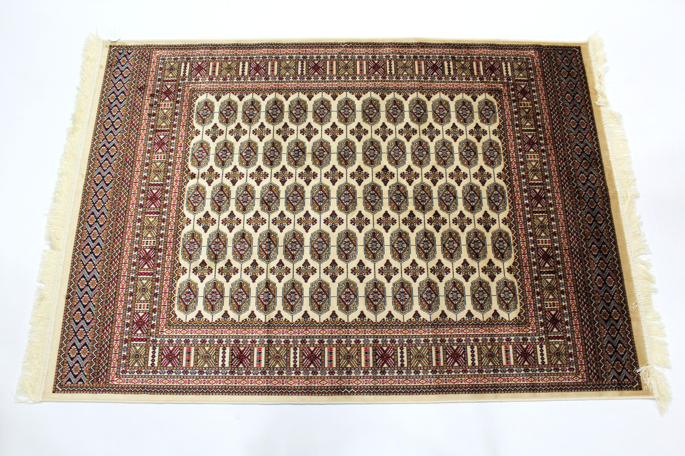 A Bokhara rug of cream & crimson ground, with five rows of thirteen guhls to centre within a wide