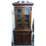 A late Victorian walnut cabinet bookcase, the upper part with a swan neck cornice,