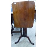 A mid 19thC mahogany tip-top table with canted corners, over a ring turned, baluster column,