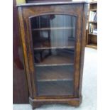 A late Victorian walnut music cabinet, surmounted by a pierced gallery, over a glazed door,