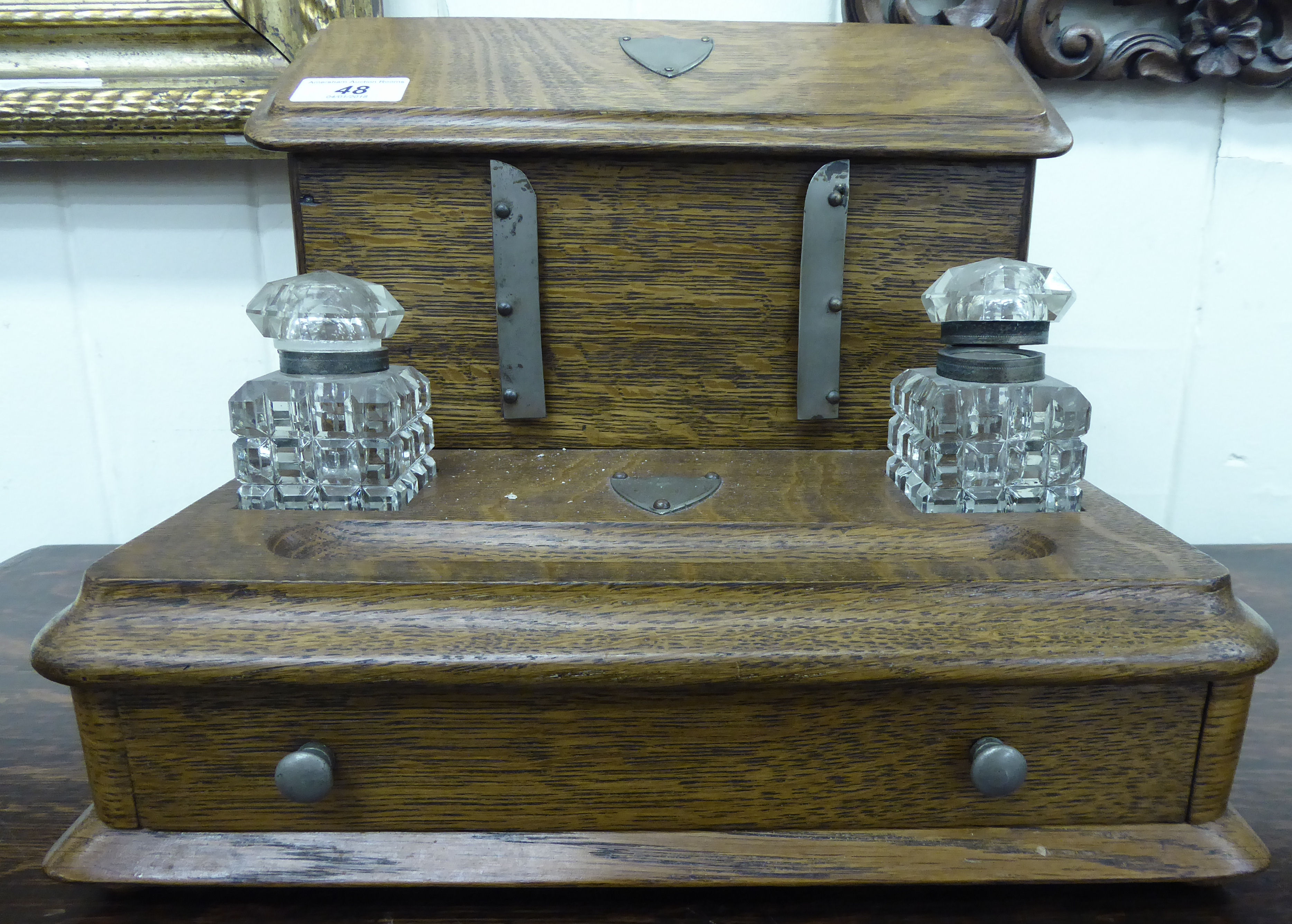 An early 20thC light oak desktop stationary box with an angled, hinged lid,