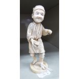 An early 20thC Japanese carved and stained ivory standing artisan figure, on a circular plinth 5.