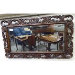 A 1930s mirror, the bevelled plate set in a boldly scroll and foliate carved frame,