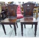 A pair of William IV mahogany hall chairs, each with a waisted plank back,