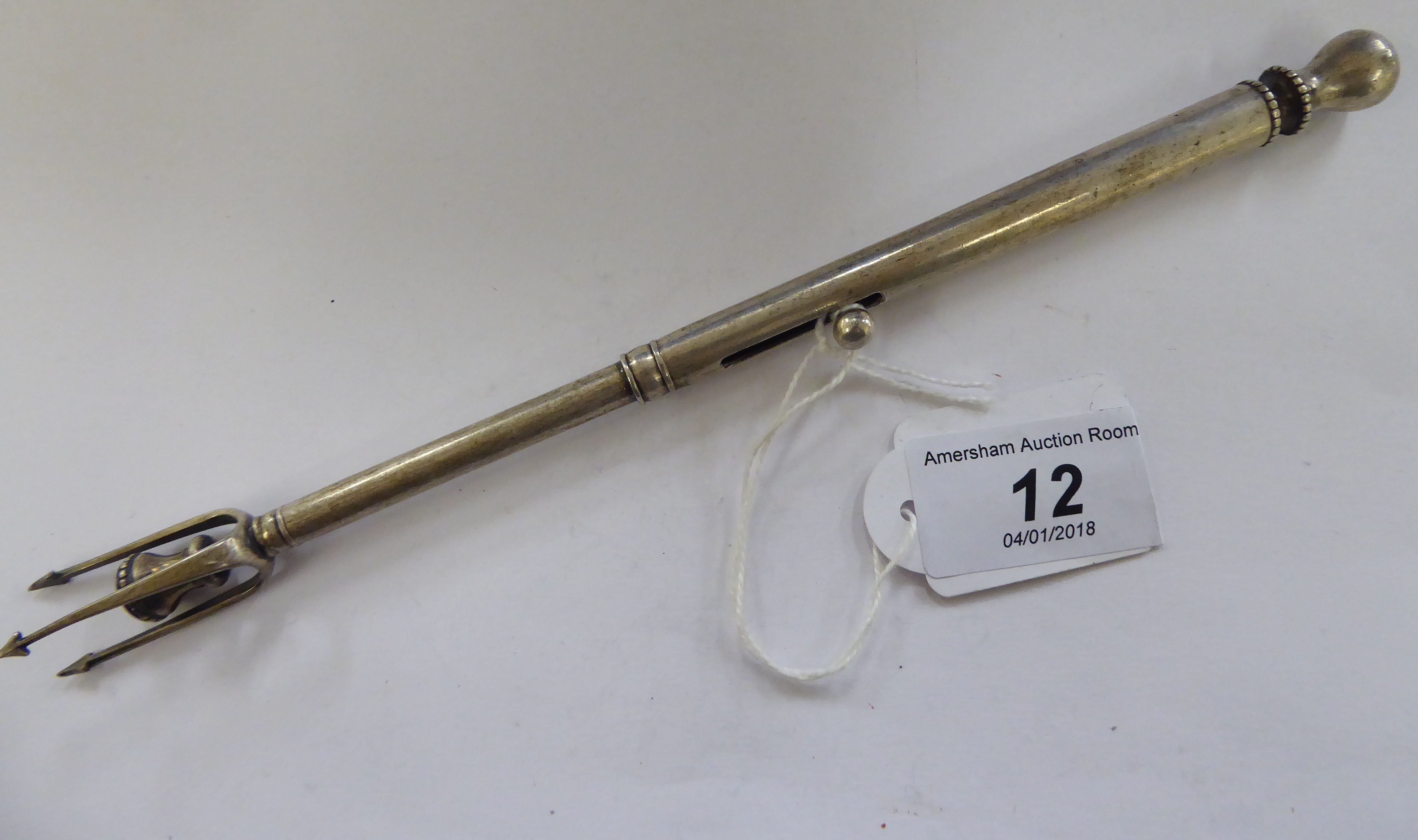 A silver plated pickle fork with a patent release action 11