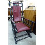 A late 19thC American ebonised hardwood framed rocking chair with a red faux hide upholstered back