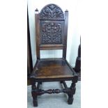 A late 18thC oak framed side chair with a floral and foliate carved back and solid seat,