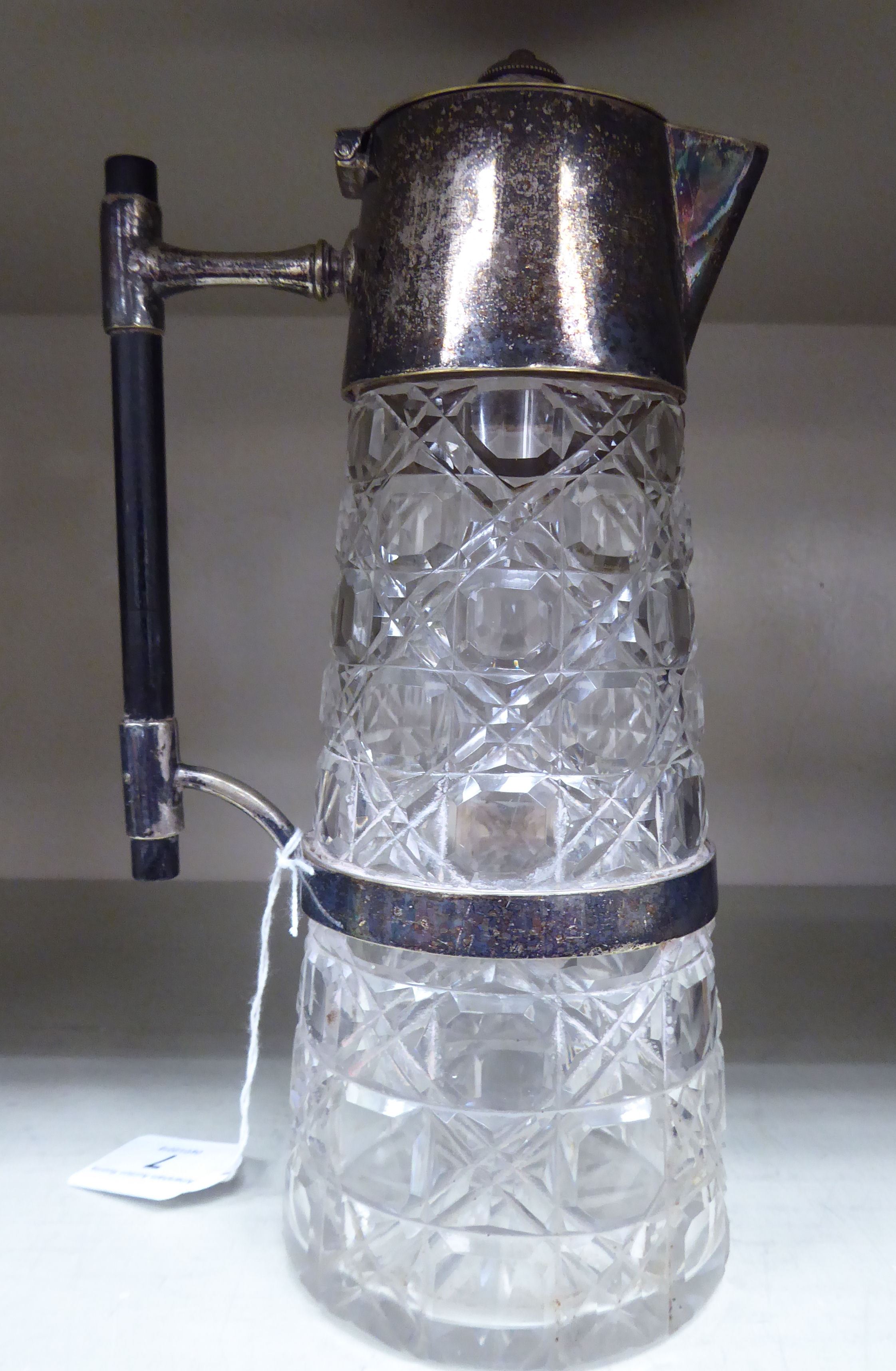 A late 19thC cylindrical cut glass claret jug with applied silver plated mounts,