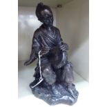 A 20thC Japanese cast and patinated bronze figure, a seated man playing a drum,