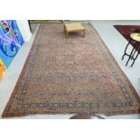 A Persian rug with repeating floral motifs on a terracotta ground 74'' x 150'' CS