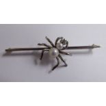 A white and yellow coloured metal spider bar brooch,