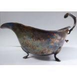 A silver sauce boat with a cut, flared rim and an acanthus topped, double C-scrolled handle,
