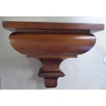 A mid 19thC mahogany clock bracket, the platform top over a cushion moulded and tapered,