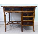 A late 19thC Orientally inspired, bamboo framed and overpainted black lacquered panelled desk,