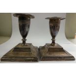 A pair of late Victorian loaded, floral cast silver dwarf candlesticks,