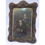 A late Victorian glazed silver photograph frame, embossed with a cartouche, shells and scrolls,