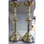 A pair of late 19thC lacquered brass ecclesiastical candlesticks, each with a wide, drip pan,