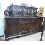 An early 20thC dark stained and carved oak bow front sideboard,