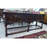 A 1920s Jacobean style stained oak dresser with three in-line panelled drawers,