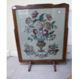 A mid 20thC mahogany framed firescreen, set with a tapestry panel depicting mixed flowers in a vase,