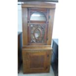 An early 20thC oak cabinet with a glazed door, enclosing three shelves, over a panelled door,