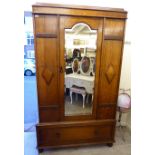 A 1920s stained oak wardrobe with a moulded cornice, a central mirrored door,