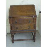 A 1930s oak bureau with a fall flap and two drawers,