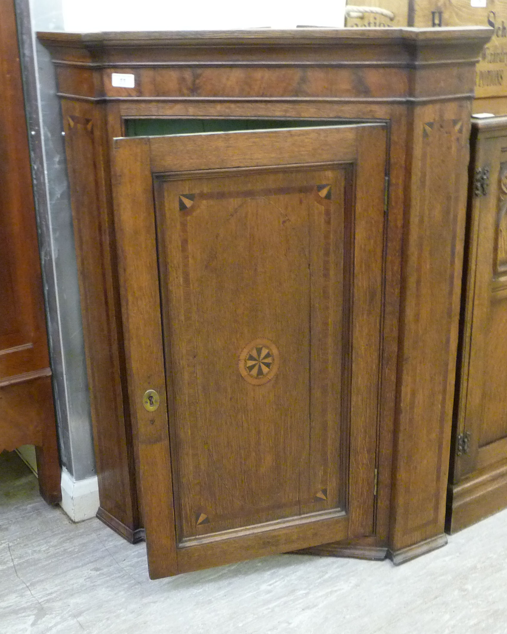 A George III mahogany crossbanded oak hanging corner cabinet with a single door,