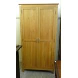 A modern light oak finished wardrobe with a moulded cornice, over a pair of panelled doors,