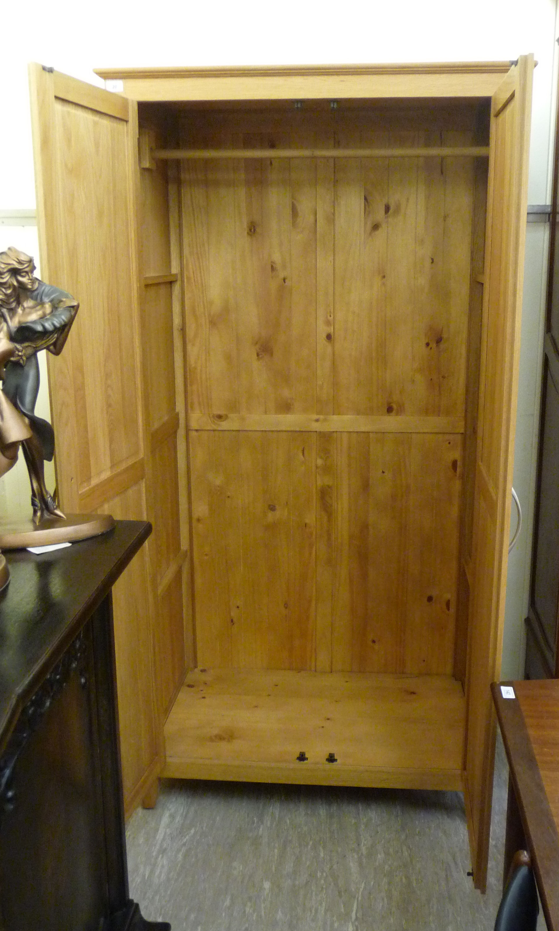 A modern light oak finished wardrobe with a moulded cornice, over a pair of panelled doors, - Image 2 of 2