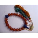 A Chinese brown and blue stone and jade bead bracelet with tassled silk pendants