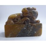 A late 19thC Chinese carved mottled green and brown soapstone seal, featuring a seated dragon-dog,