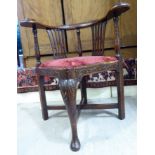 A 19thC mahogany framed corner chair with a raised crest, on a level, foliate scroll carved,