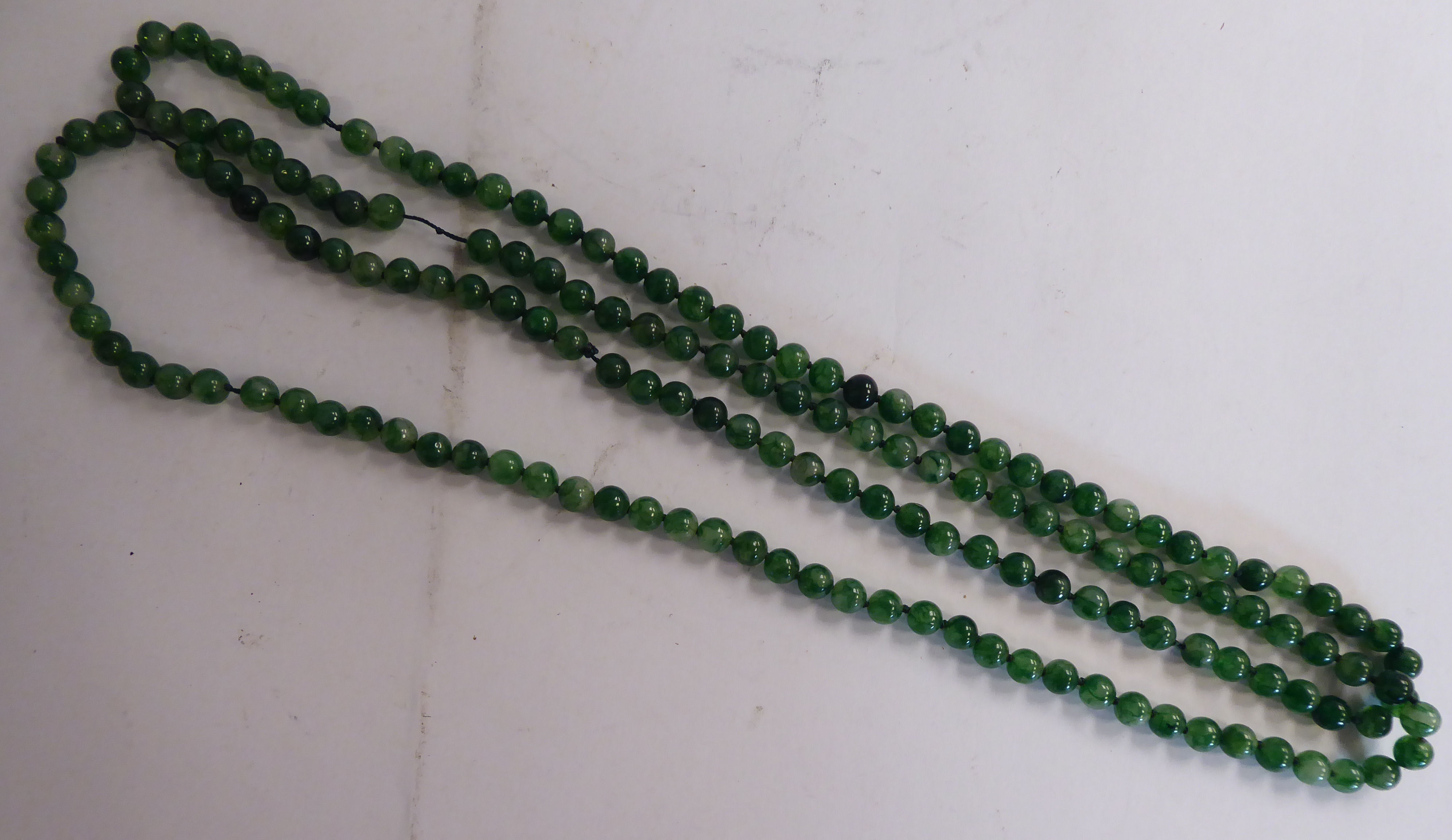 A Chinese uniform small round seaweed green jade bead necklace