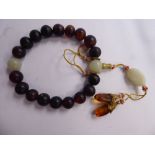 A Chinese dark amber coloured and jade bead bracelet with pendants