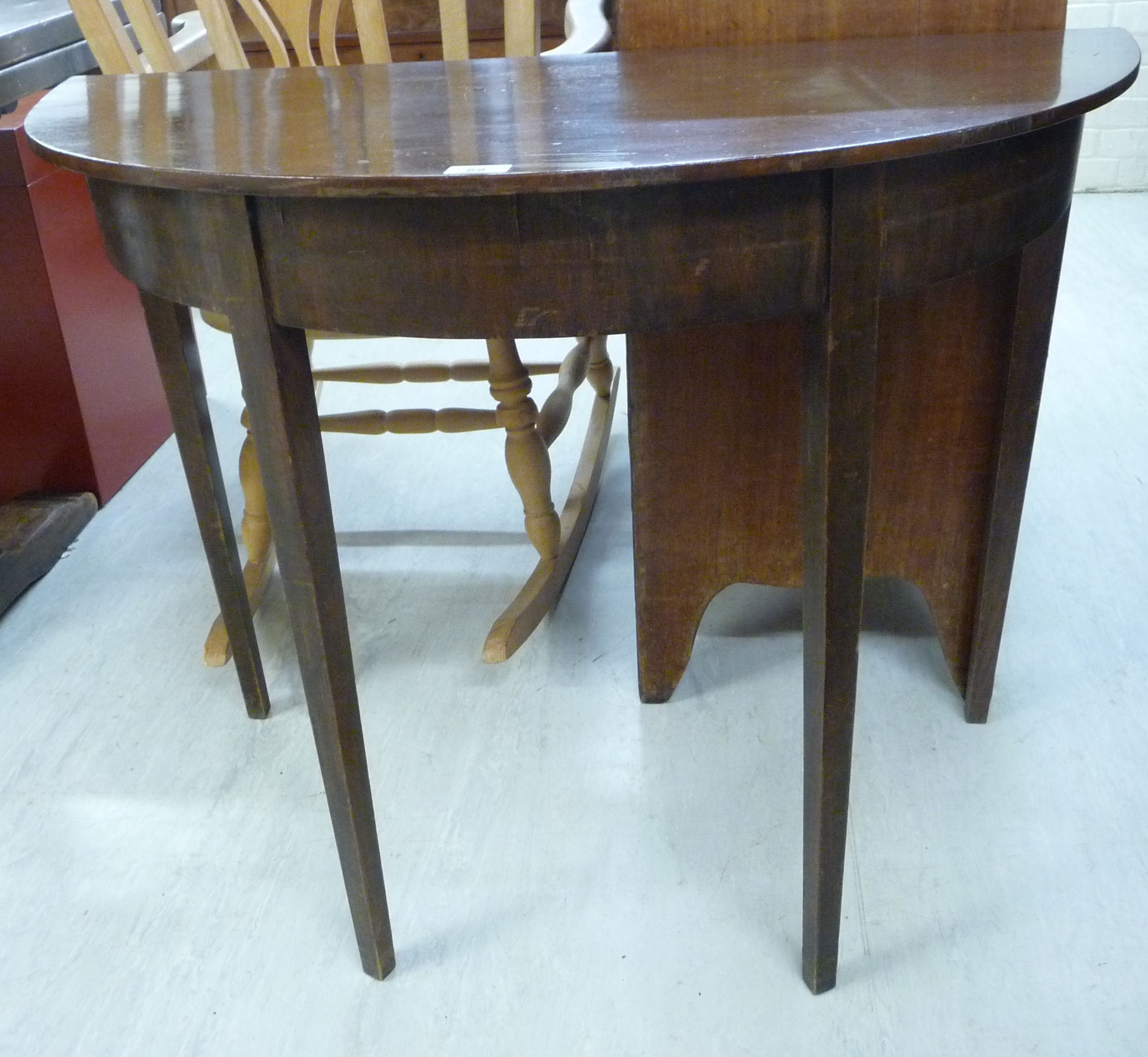 An early 20thC mahogany demi-lune console table with a straight apron, raised on square,