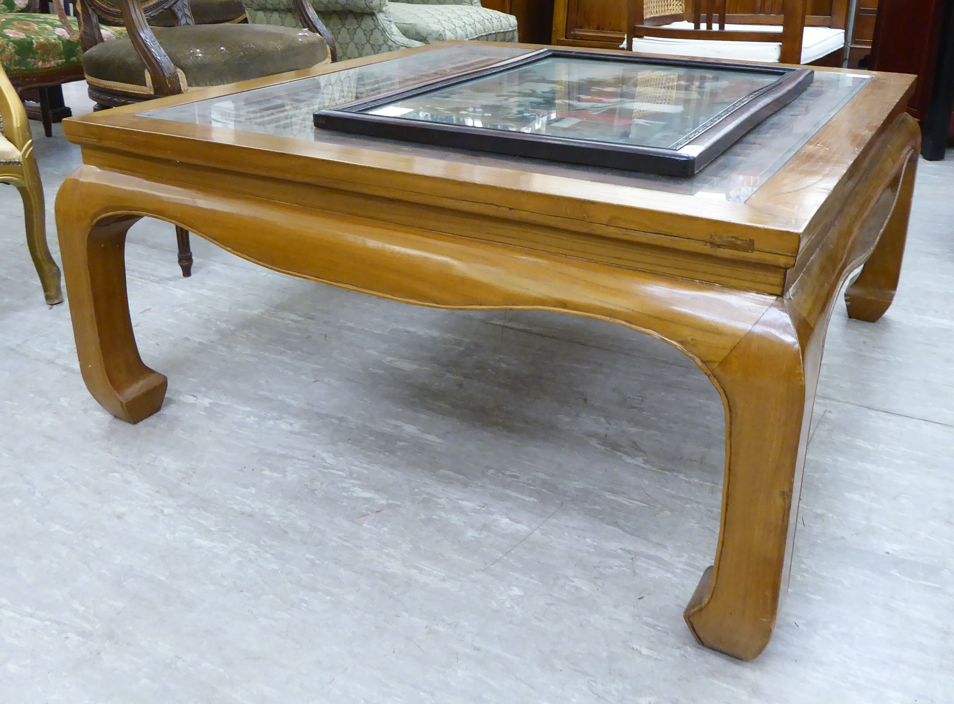 A modern Chinese lacquered elm coffee table, the openwork top with a glass panel, raised on carved,